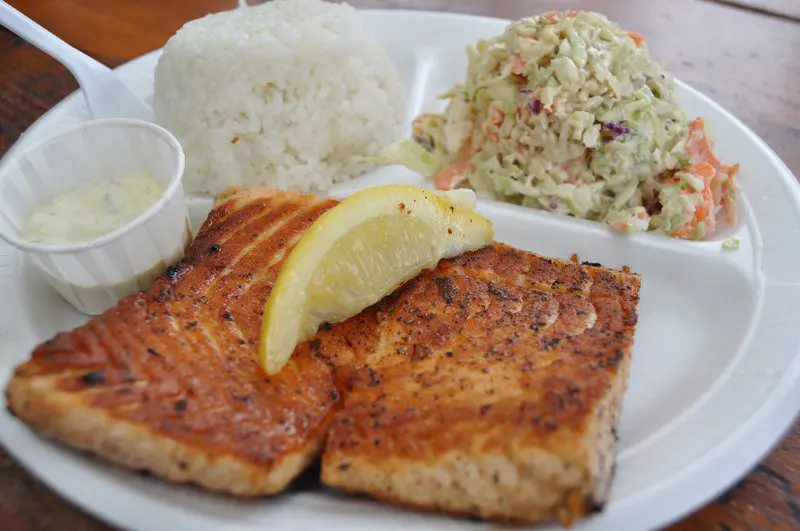 A plate of food with fish, rice and salad.