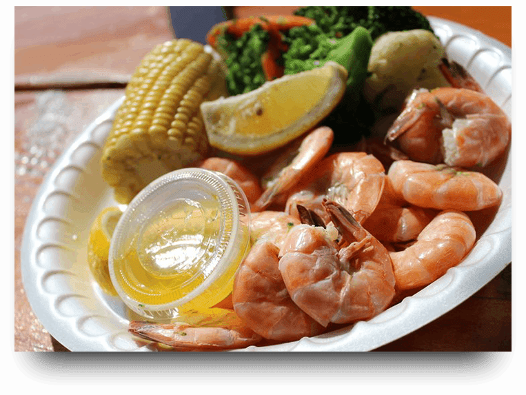 A plate of shrimp, corn and broccoli with lemon.