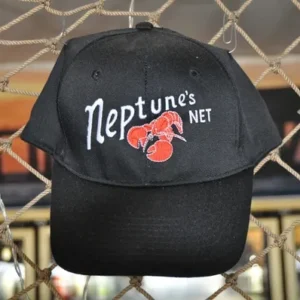 A black hat hanging on the fence of a cage.