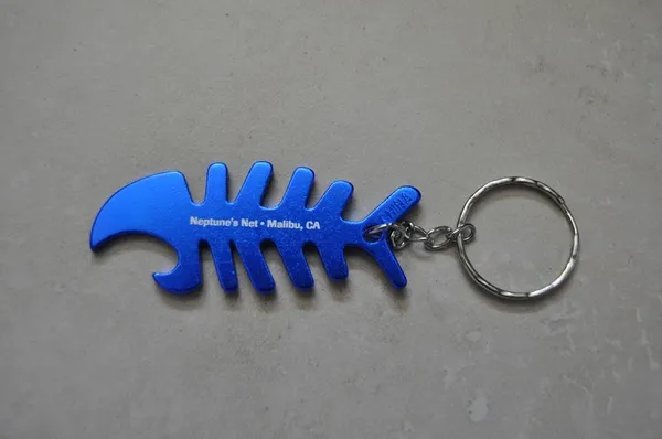 A blue fish shaped bottle opener with a keychain.